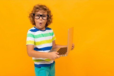 A boy in glasses holding a laptop